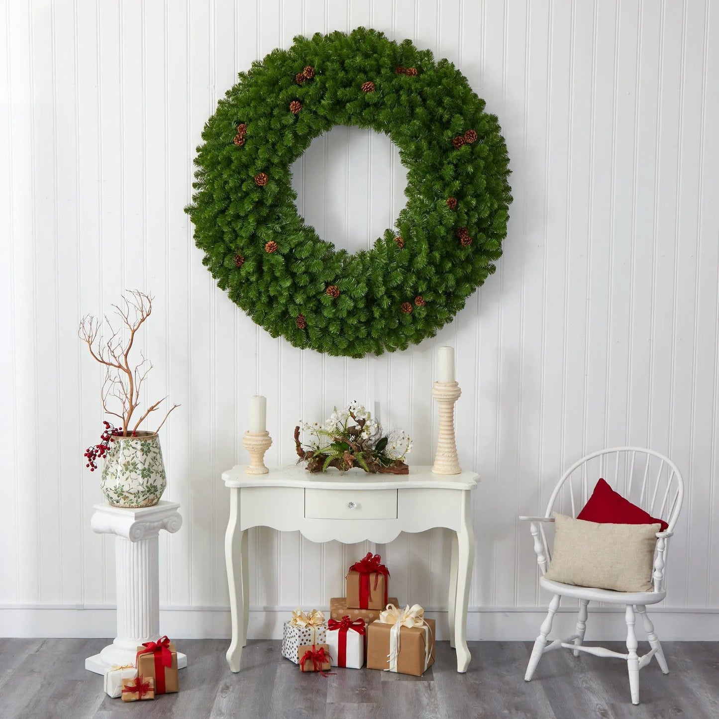 Giant artificial Christmas wreath in bright green with pine cones on a white paneled wall on Tampa Home & Garden Store