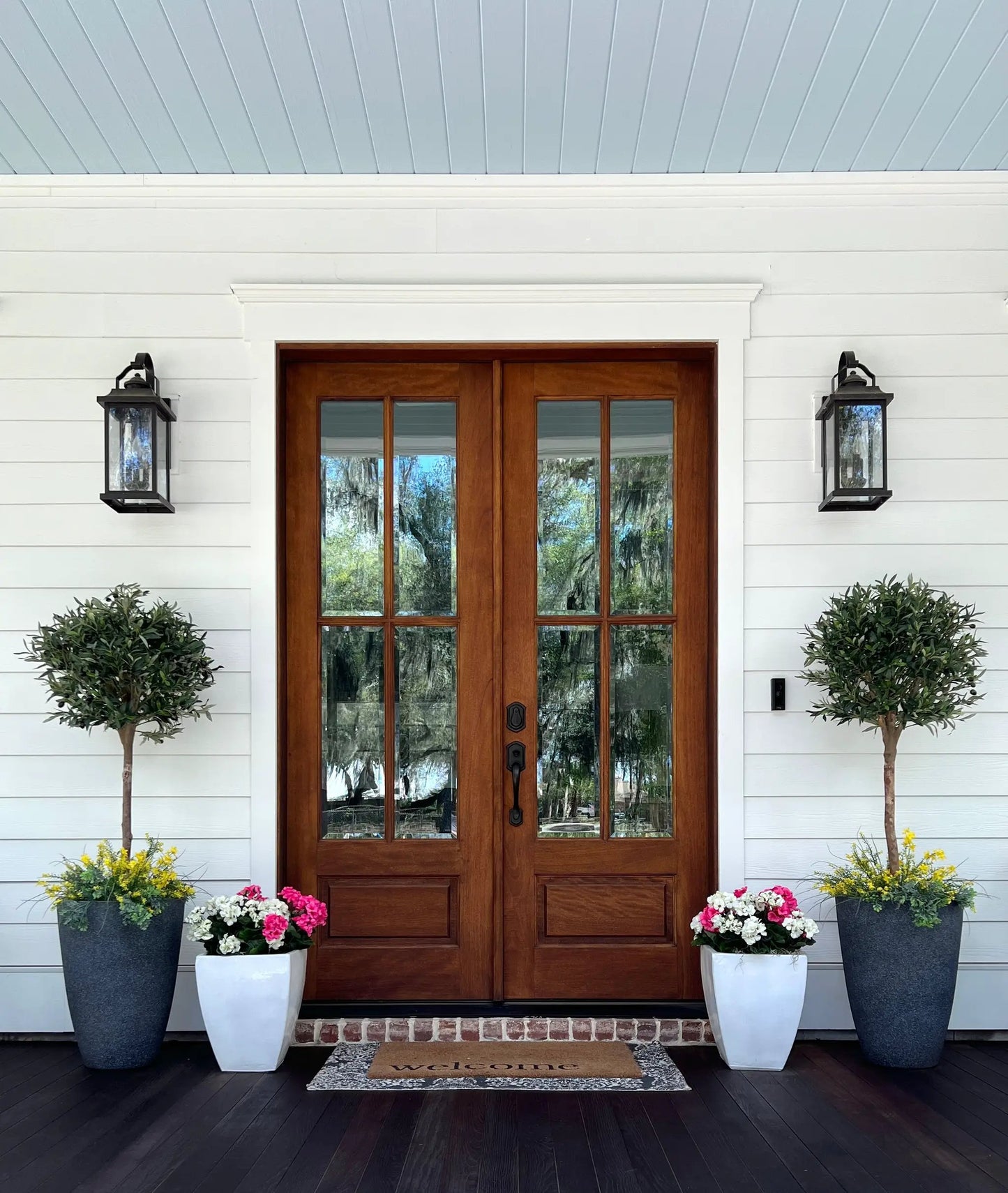 Nearly Natural 5 Foot Olive Topiary Artificial Tree flanks a wooden front door on Tampa Home & Garden Store
