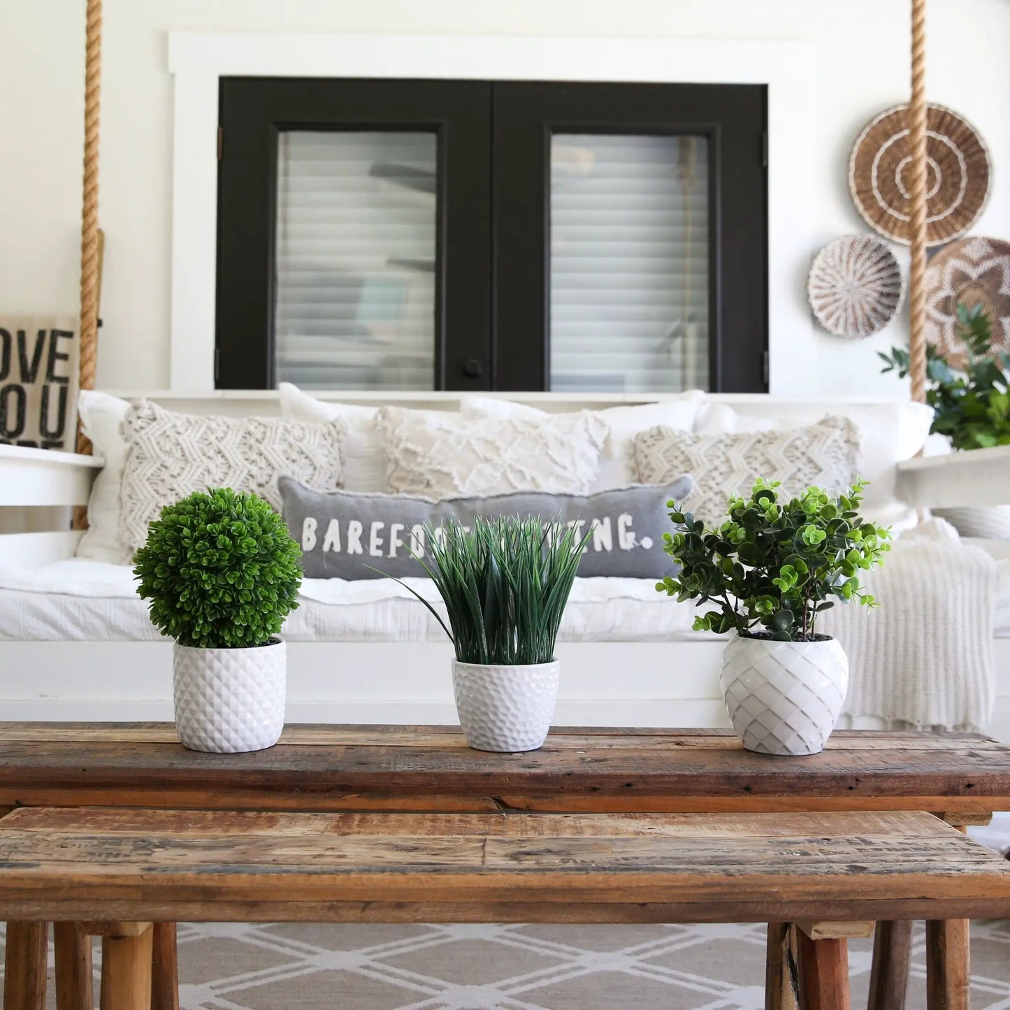 Four 9 Inch artificial grass plants in white textured planters on a rustic wood table on Tampa Home & Garden Store