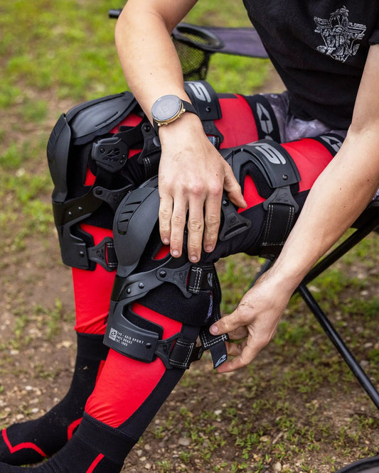 Axis Sport 2025 Knee Brace, EVS Sports, pair of black shell knee guards on red/black gear on Tampa Home & Garden Store