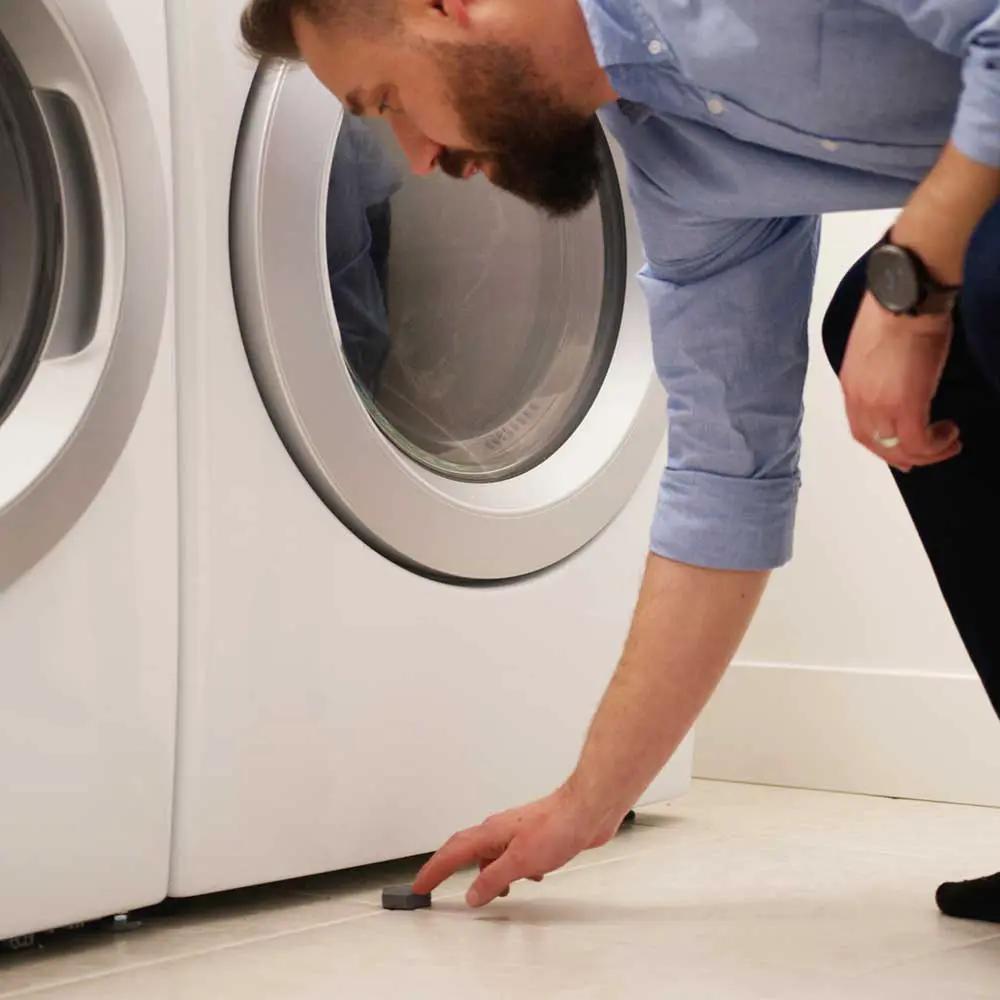 Man in a blue shirt crouches by a front-loading washer, touching a small black timer on the floor on Tampa Home & Garden Store