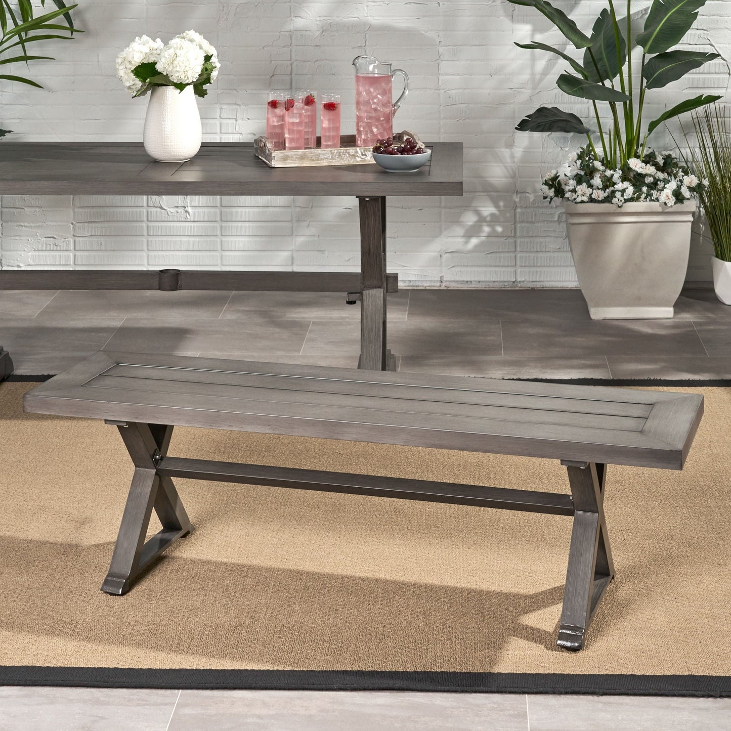 Modern dark gray aluminum outdoor dining bench with X base on a deck on Tampa Home & Garden Store