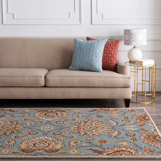 Conesus hand tufted gray wool area rug with blue/tan floral pattern in a living room setting on Tampa Home & Garden Store
