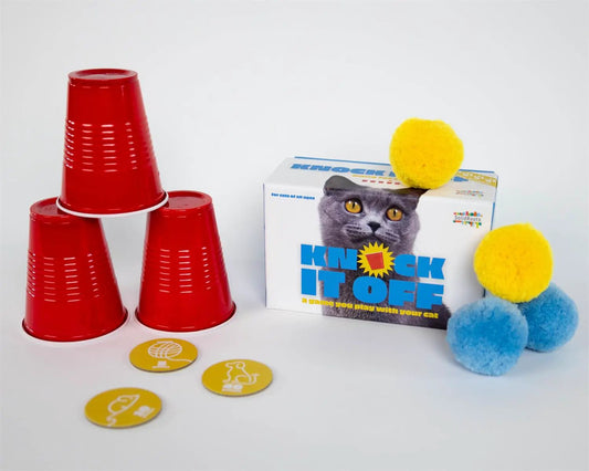 Knock It Off cat game box with three red stacking cups and fluffy yellow and blue pom-poms on Tampa Home & Garden Store
