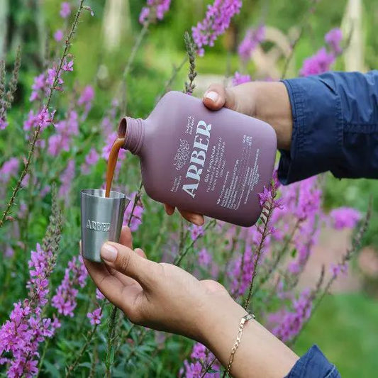 Organic Bio Fungicide bottle from House Plant Shop, purple bottle poured into cup near flowers on Tampa Home & Garden Store
