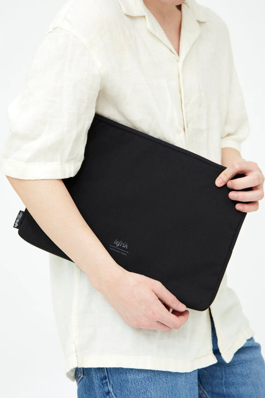 Capture 15-inch black laptop case by Lefrik USA, sleek sleeve held under a cream shirt on Tampa Home & Garden Store
