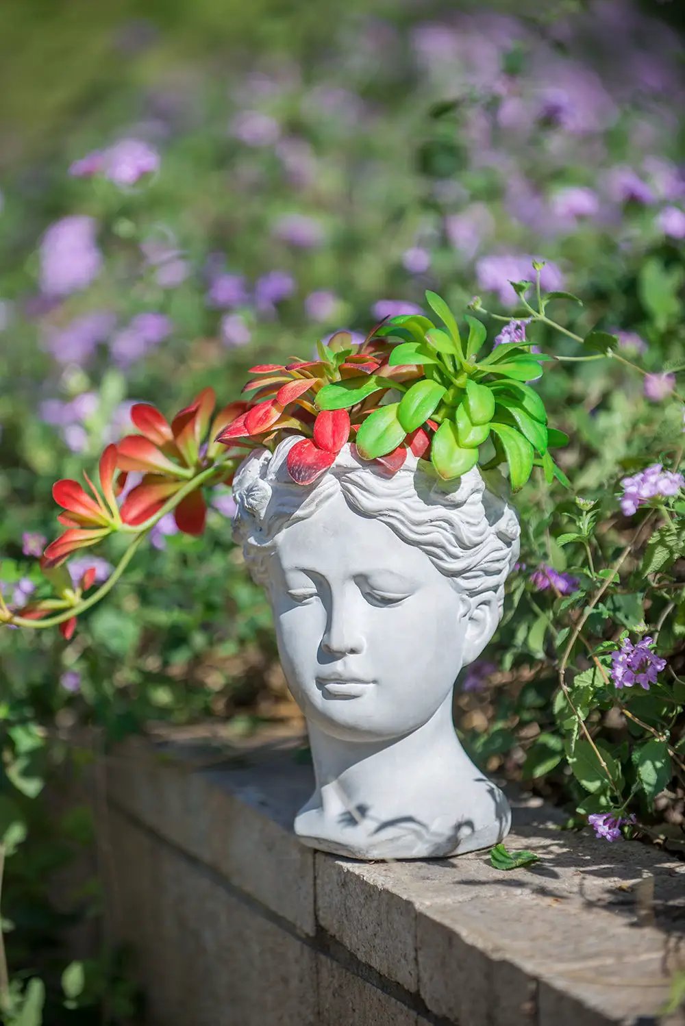 Greek-style cement bust planter with green and red succulents on a gray head in a garden decor on Tampa Home & Garden Store