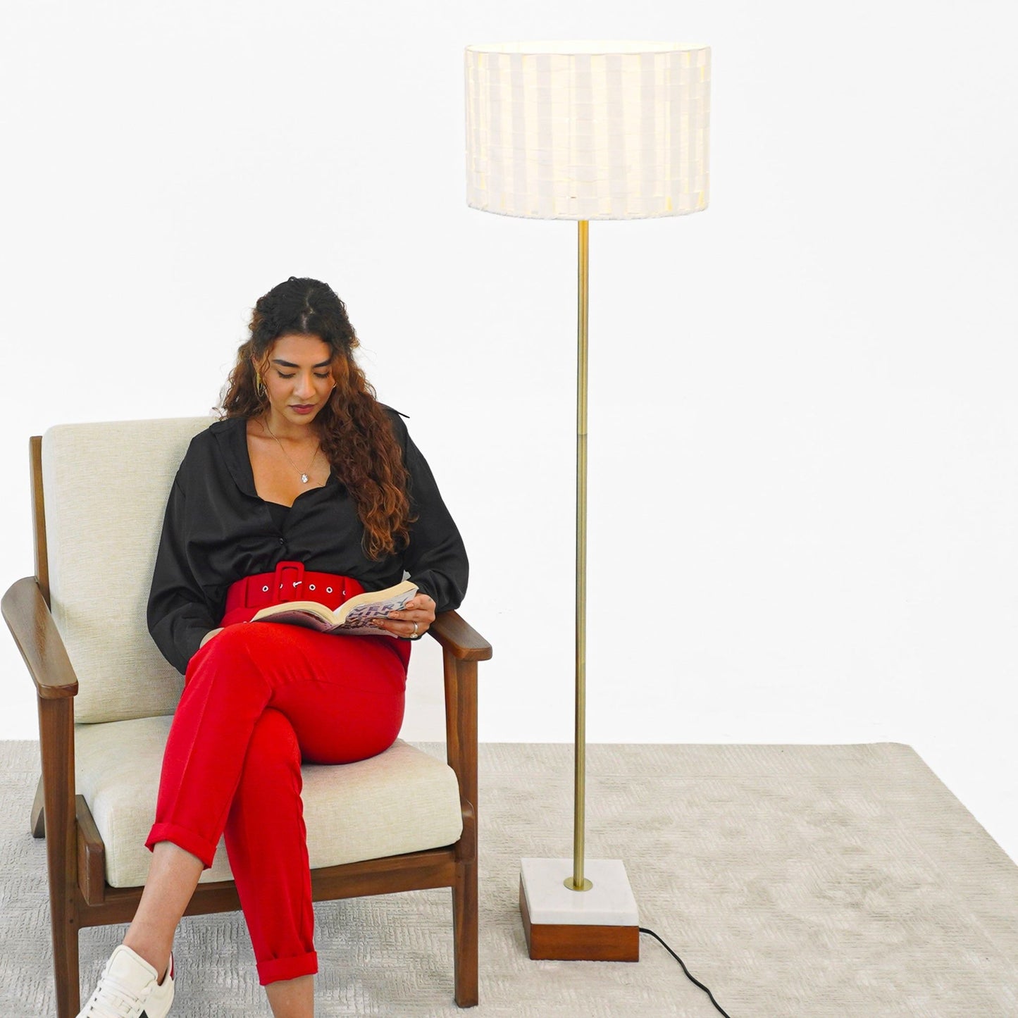 Viora Floor Lamp Gold by HouseOfZazla with white shade beside a seated woman on Tampa Home & Garden Store