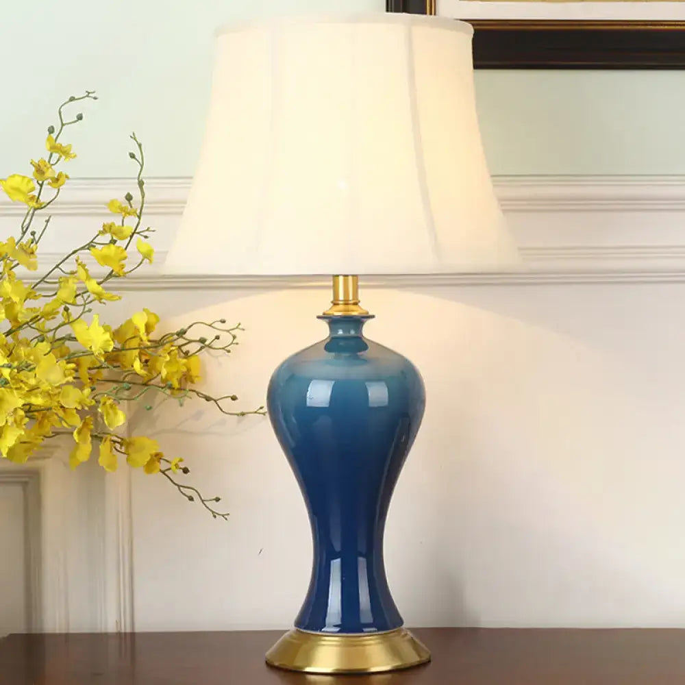 Blue ceramic table lamp by Decorbites with white fabric shade and brass base on wood table on Tampa Home & Garden Store