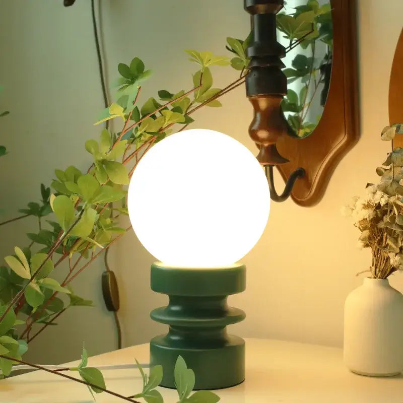 Chrome Glass USB Lamp with white globe and green base on a desk beside plants on Tampa Home & Garden Store