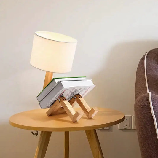 Decorbites wooden robot desk lamp with white shade on round table, books between its legs on Tampa Home & Garden Store