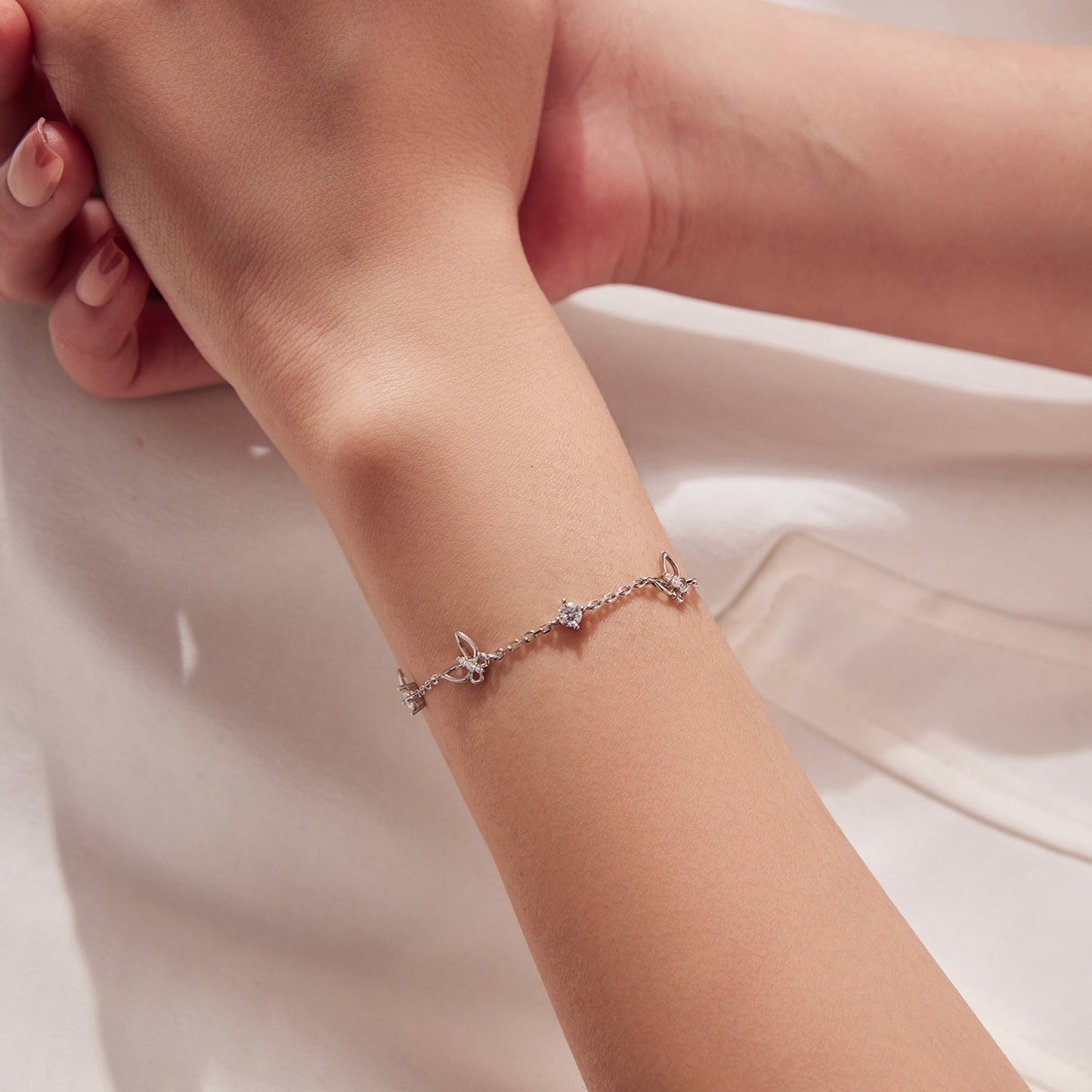 Bracelet: sterling silver with white gold plating, moissanite and butterfly charms on wrist on Tampa Home & Garden Store