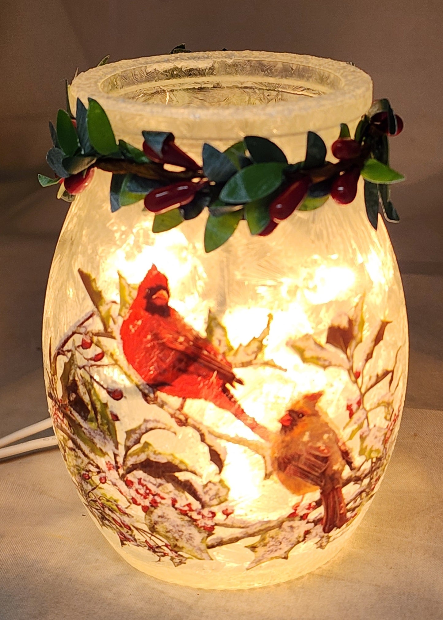 Lighted glass jar with frosted finish, garland of green leaves and cardinals around rim on Tampa Home & Garden Store