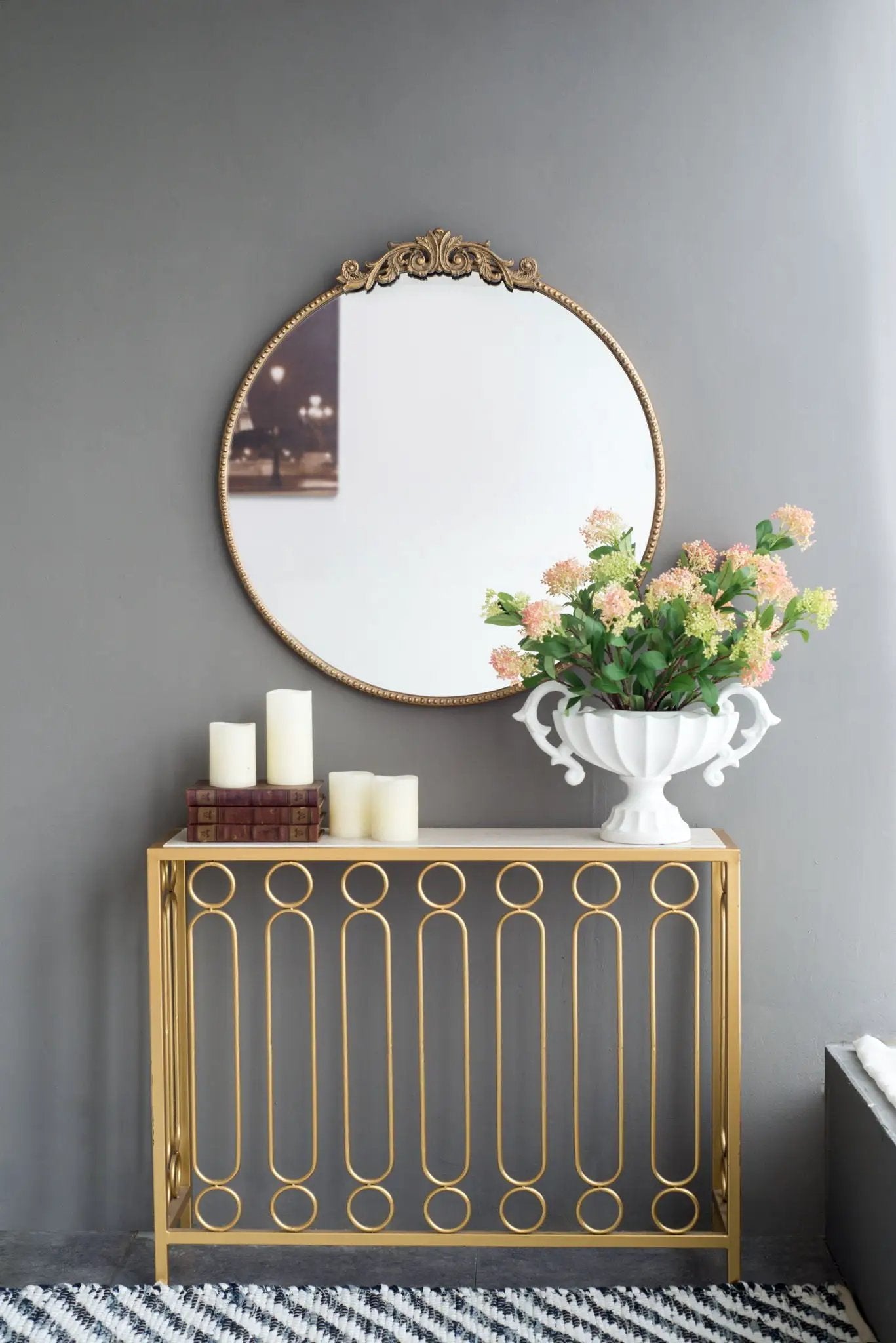 Round wall mirror with ornate gold Baroque frame and crest over a circular-motif console on Tampa Home & Garden Store