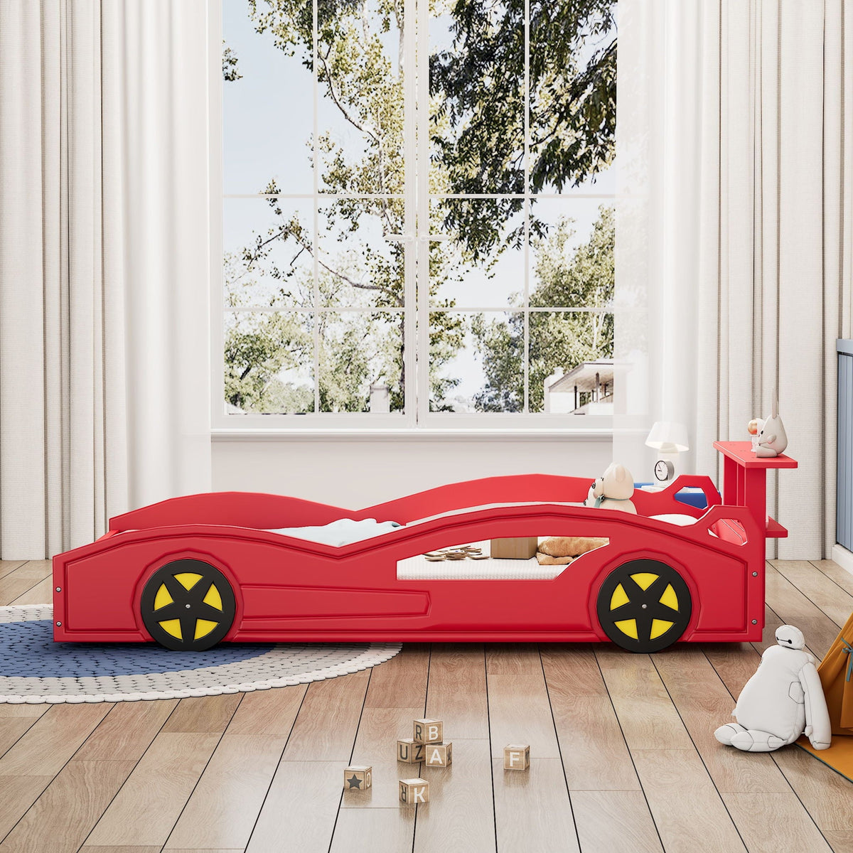Red race car platform bed with yellow wheels in a kid's room with blocks nearby on Tampa Home & Garden Store