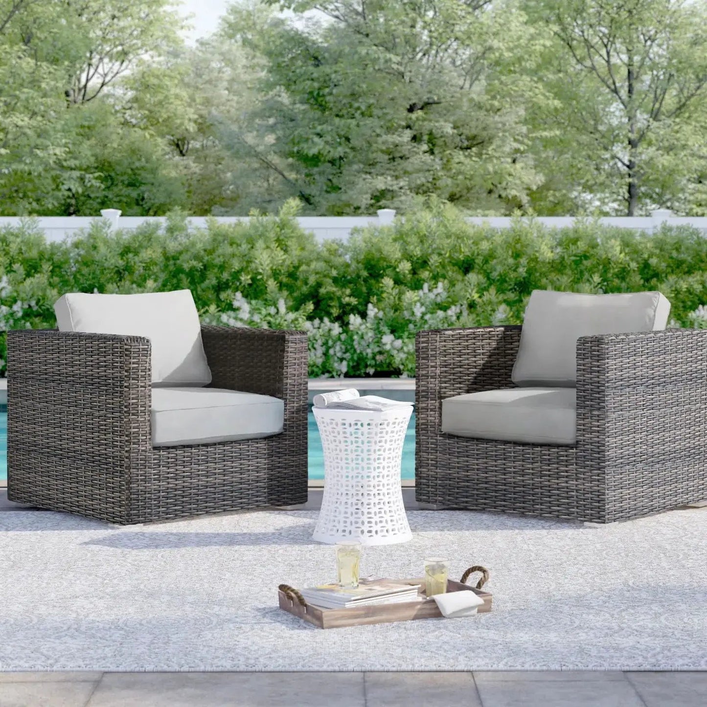 Two dark brown wicker patio arm chairs with beige cushions and a white lattice table by pool on Tampa Home & Garden Store