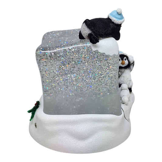 Cube à neige lumineux tourbillonnant avec des pingouins