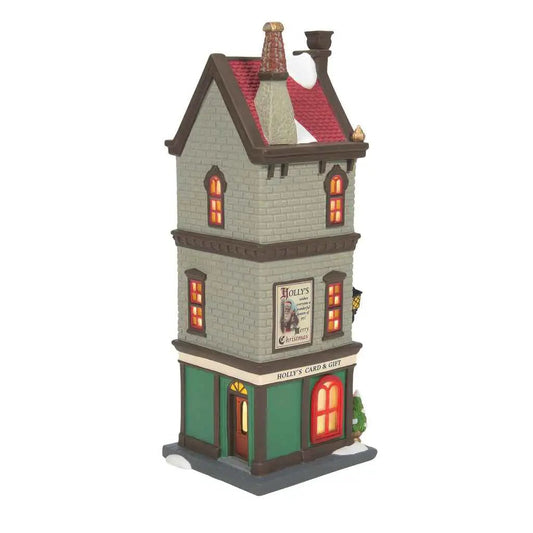 Holly's Card & Gift holiday village storefront gray brick, green ground floor, warm lit windows on Tampa Home & Garden Store