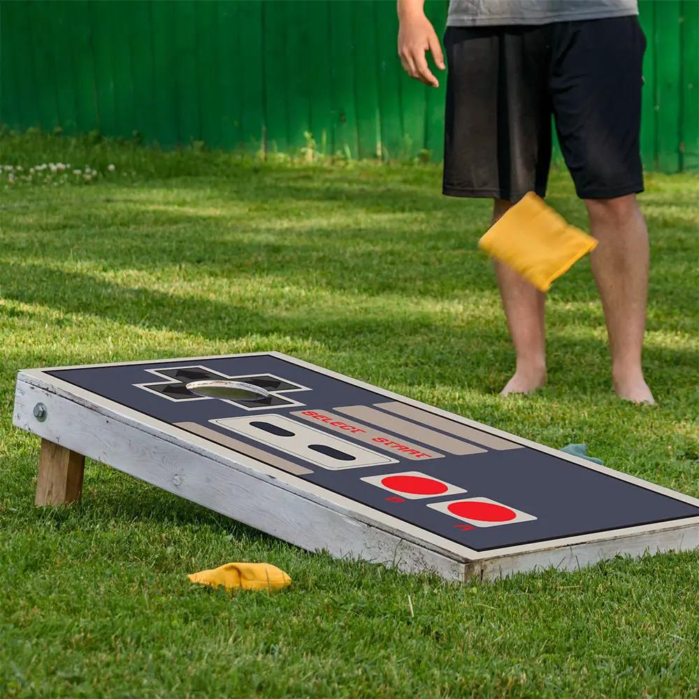 Cornhole board wrap with navy background and red accents, hole visible on grass with yellow bean bag on Tampa Home & Garden Store