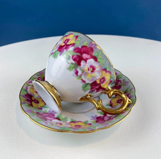 Vintage teacup and saucer set with vibrant pansies in pink yellow and purple, and gold trim on Tampa Home & Garden Store