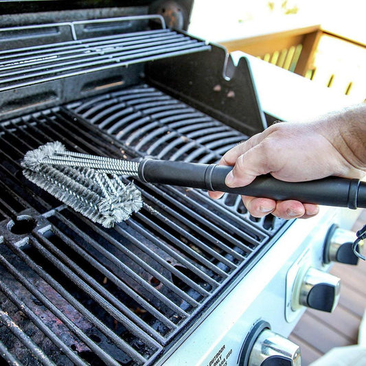 Grill brush with stainless steel wire bristles and black handle cleaning a gas grill grate on Tampa Home & Garden Store