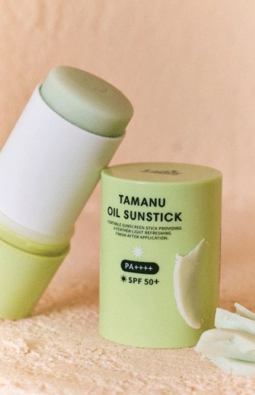 Tamanu Oil Sunstick SPF50+ PA++++ green tube with pale balm exposed on sandy backdrop on Tampa Home & Garden Store