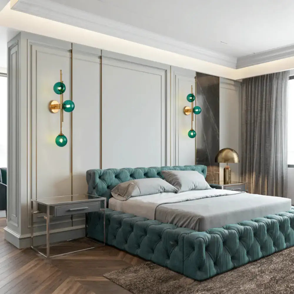 Brass glass orb sconces pair with teal spheres flanking a tufted teal bed in a luxury bedroom on Tampa Home & Garden Store