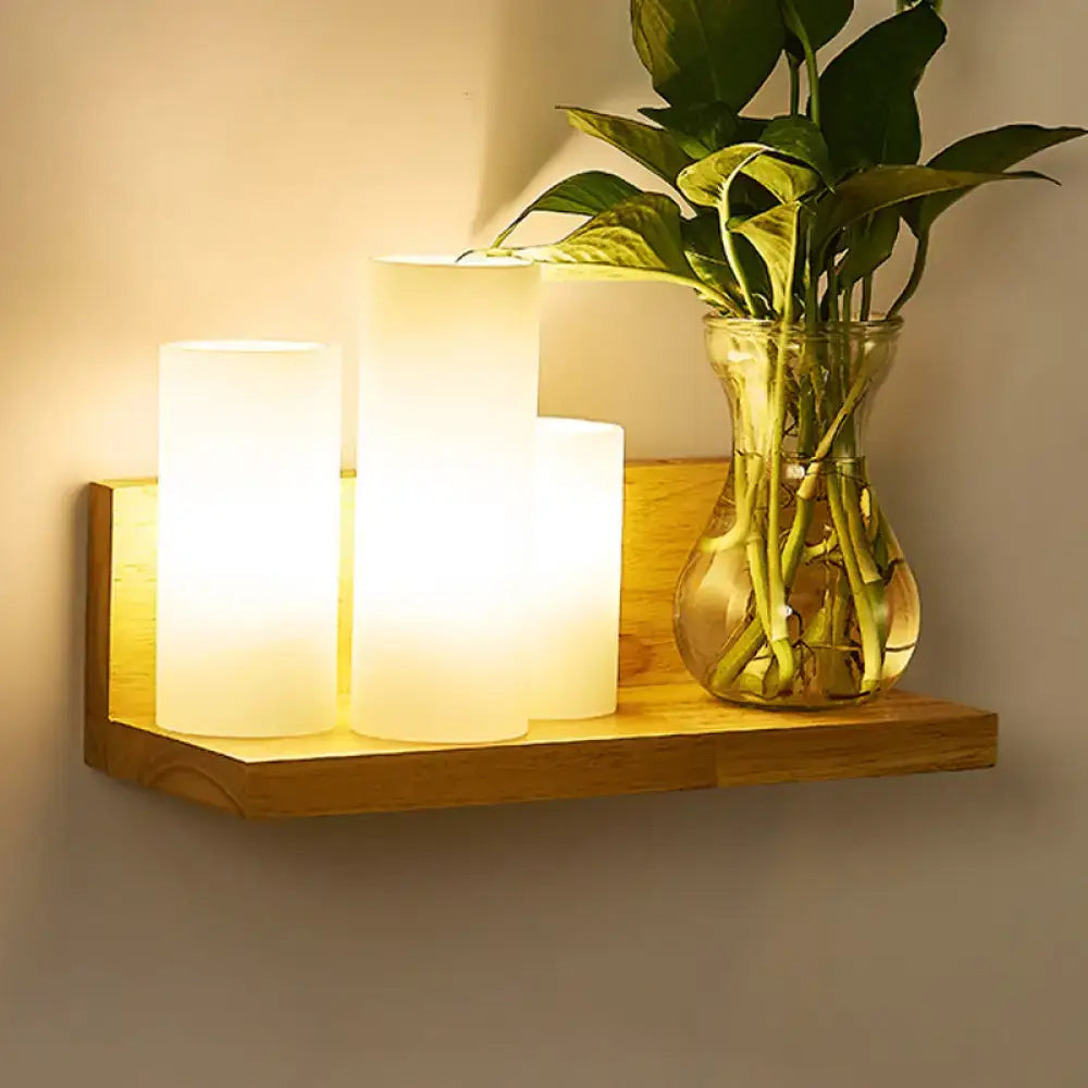 Wood Geometric Wall Sconce with warm frosted lamps on a wooden shelf beside a plant vase on Tampa Home & Garden Store
