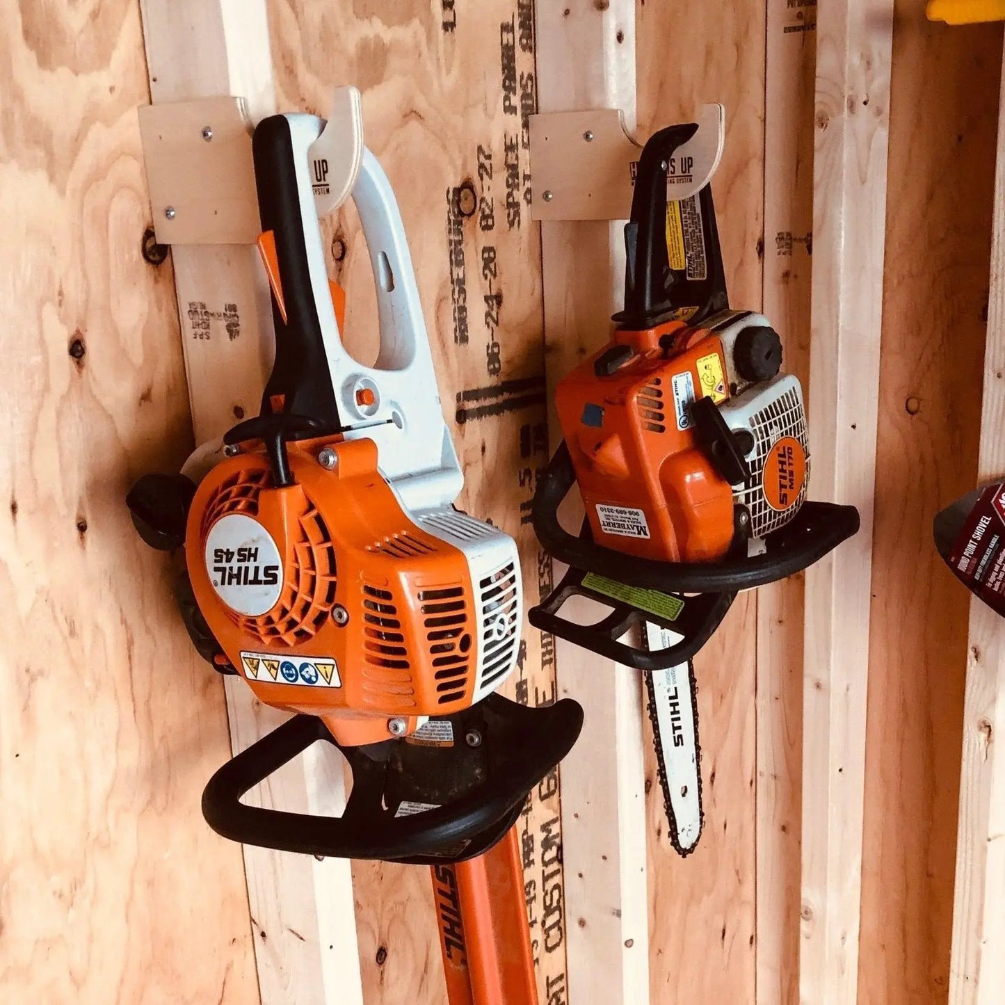 Misc Hook Shed Organizer for Yard Storage holding two orange Stihl chainsaws on Tampa Home & Garden Store