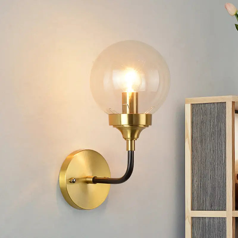 Brass curved wall sconce with clear glass globe by Decorbites on Tampa Home & Garden Store