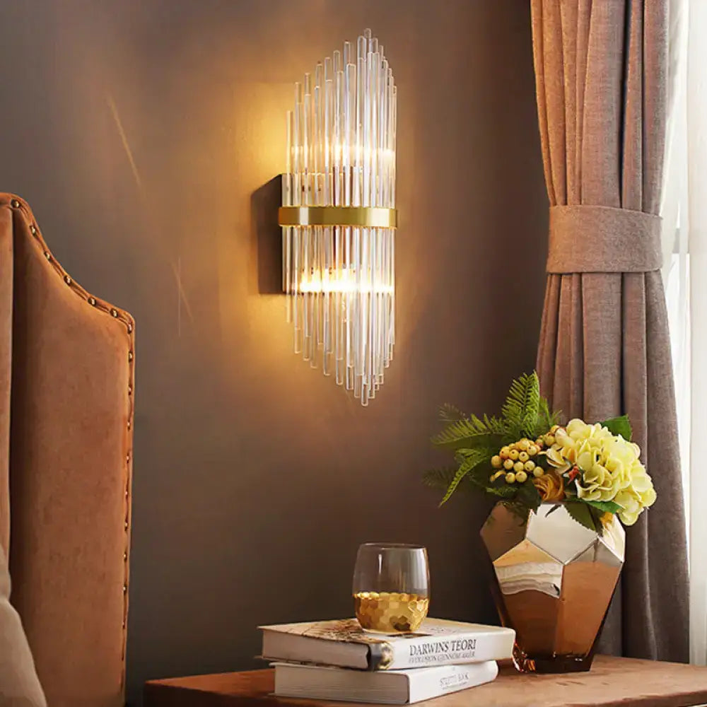 Brass fluted glass sconce with trailing arm design, wall-mounted, warm glow on Tampa Home & Garden Store