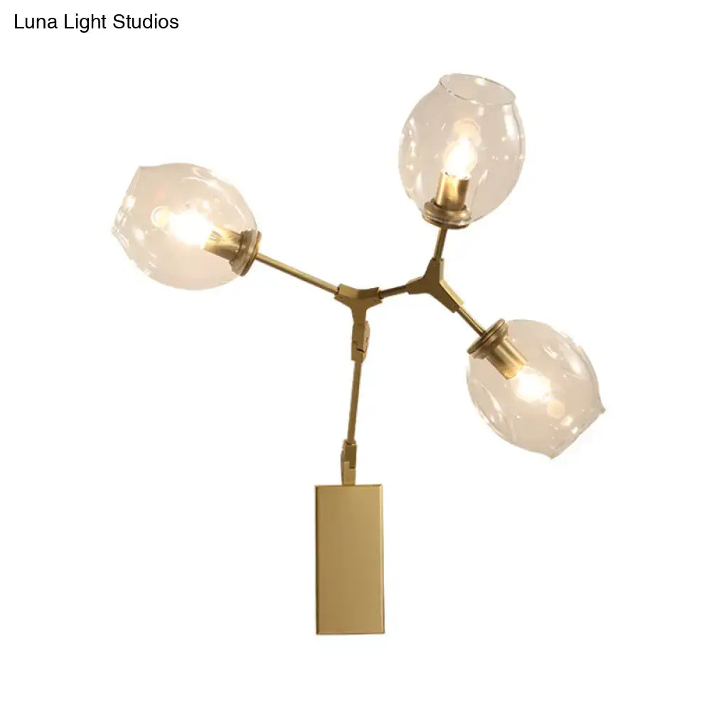 Gold branch wall sconce with brass finish and three glass globe shades on Tampa Home & Garden Store