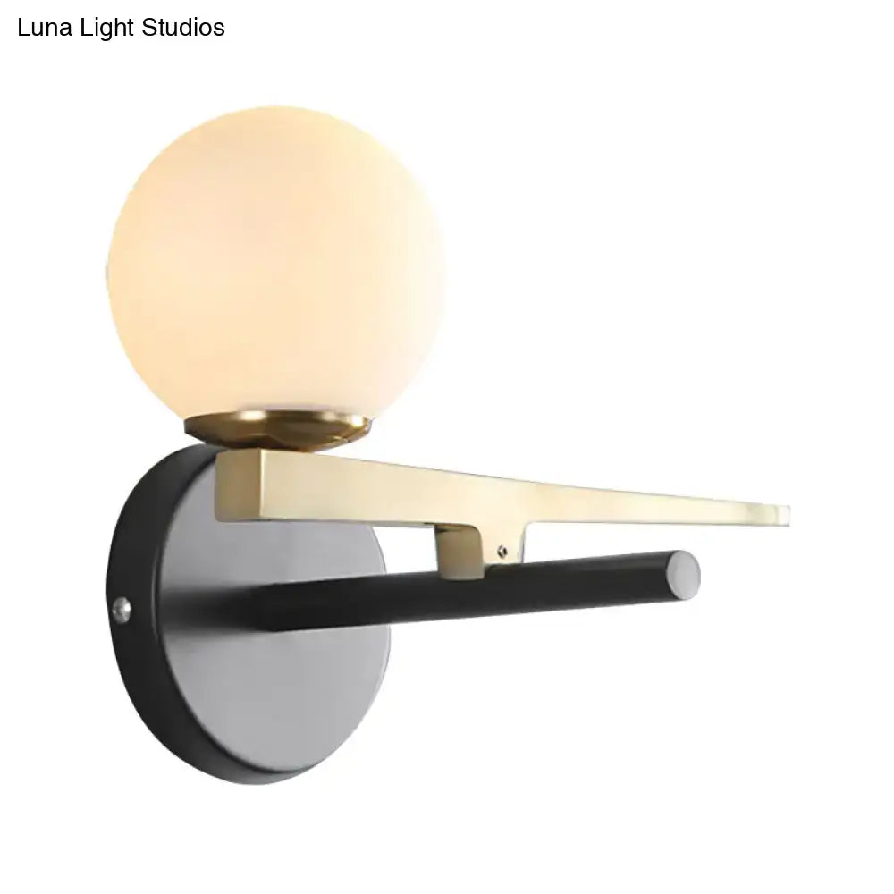 Gold glass sphere wall light with brass arm and black backplate on Tampa Home & Garden Store