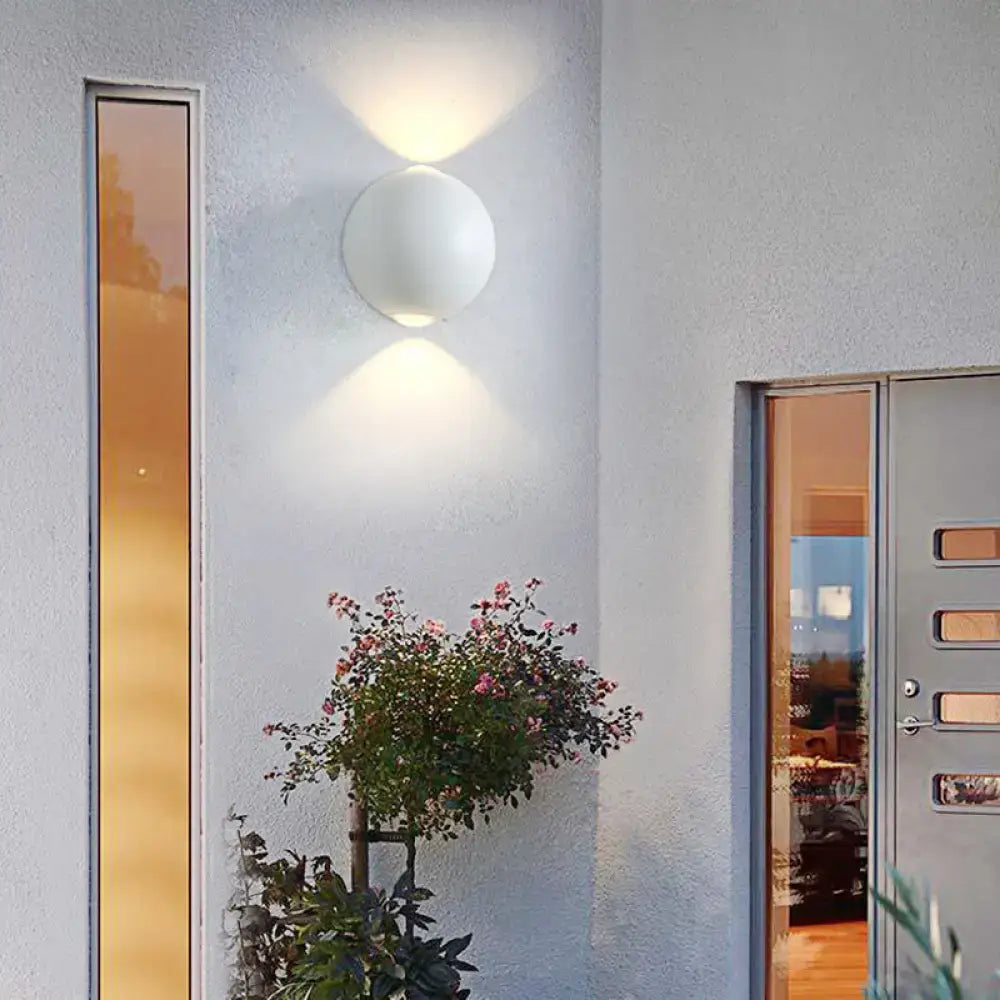 Decorbites white spherical outdoor sconce mounted on textured exterior wall beside glass door on Tampa Home & Garden Store