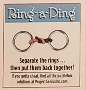Ring-a-Ding puzzle toy: two metal rings linked by a pink and black cord in a gift box on Tampa Home & Garden Store