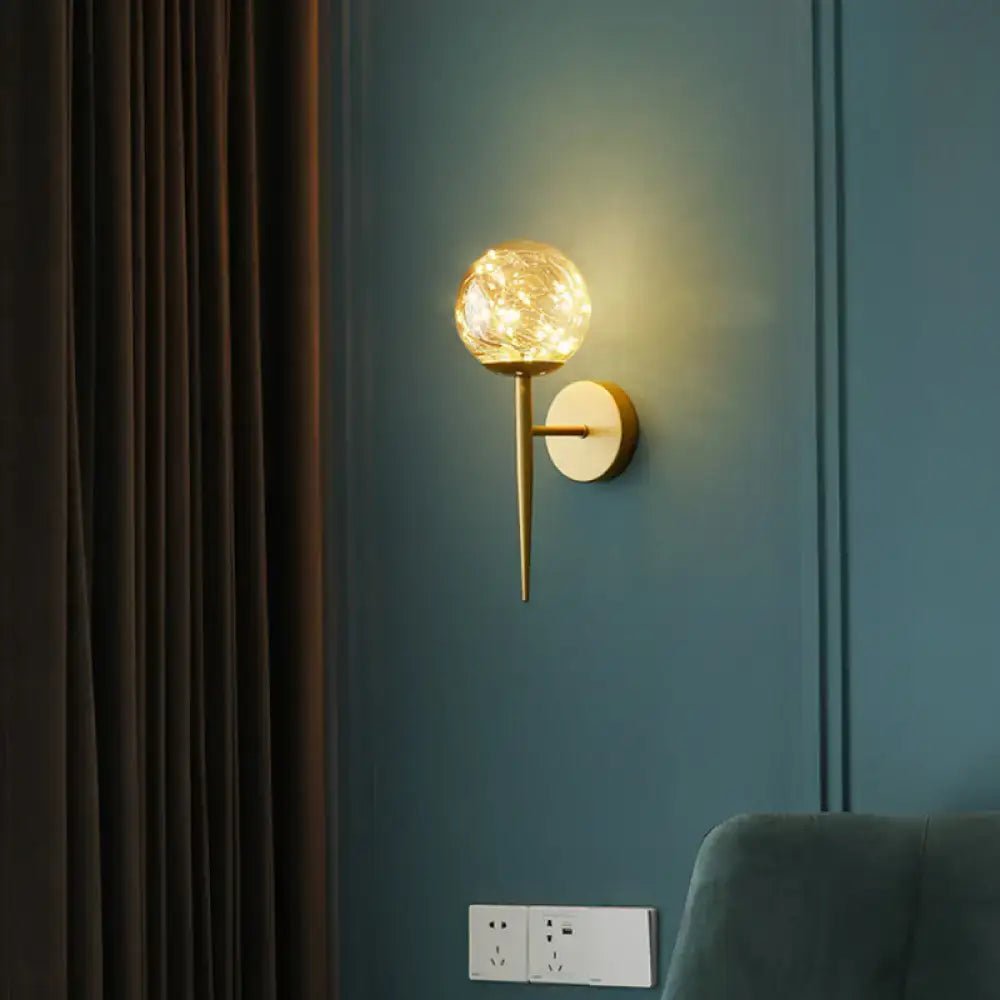 Gold glass globe wall sconce with brass cone arm and round backplate, warm glow on Tampa Home & Garden Store