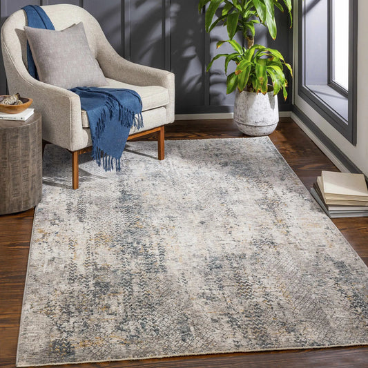 Odell Abstract Fringe Rug in mustard and gray under beige chair with a blue throw in living room on Tampa Home & Garden Store