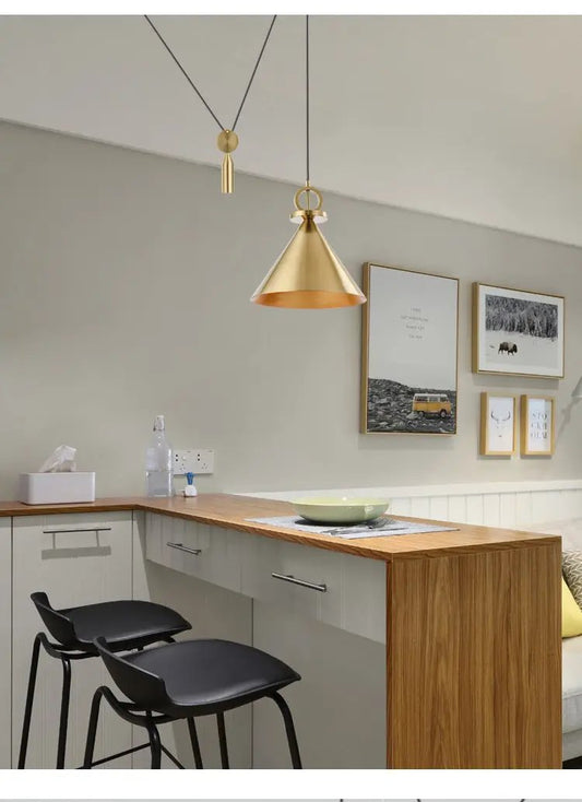 Retractable brass chandelier pendant above a kitchen island with black bar stools on Tampa Home & Garden Store