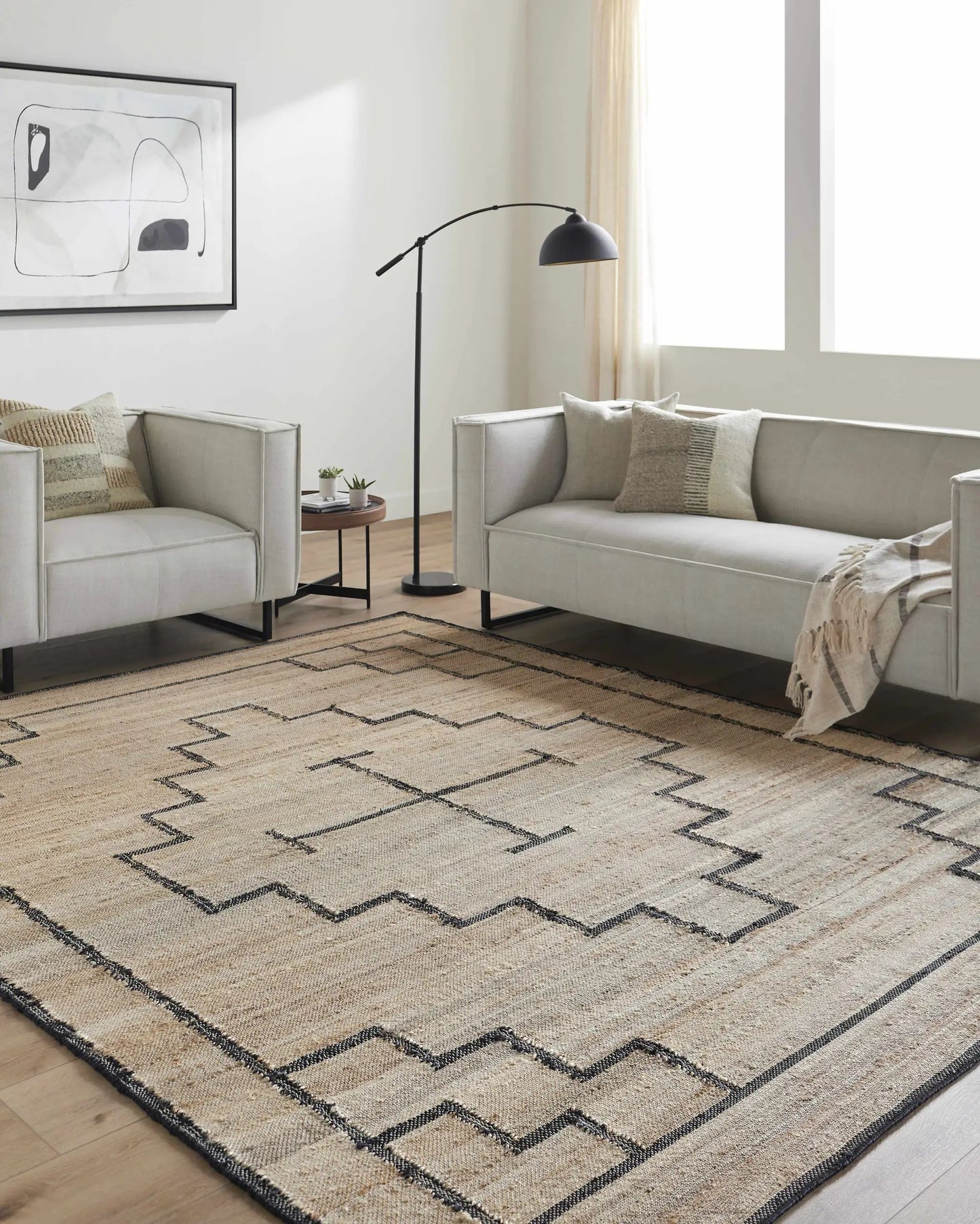Robyn Handmade Jute Carpet rug in tan and black with a zigzag border in a modern living room on Tampa Home & Garden Store