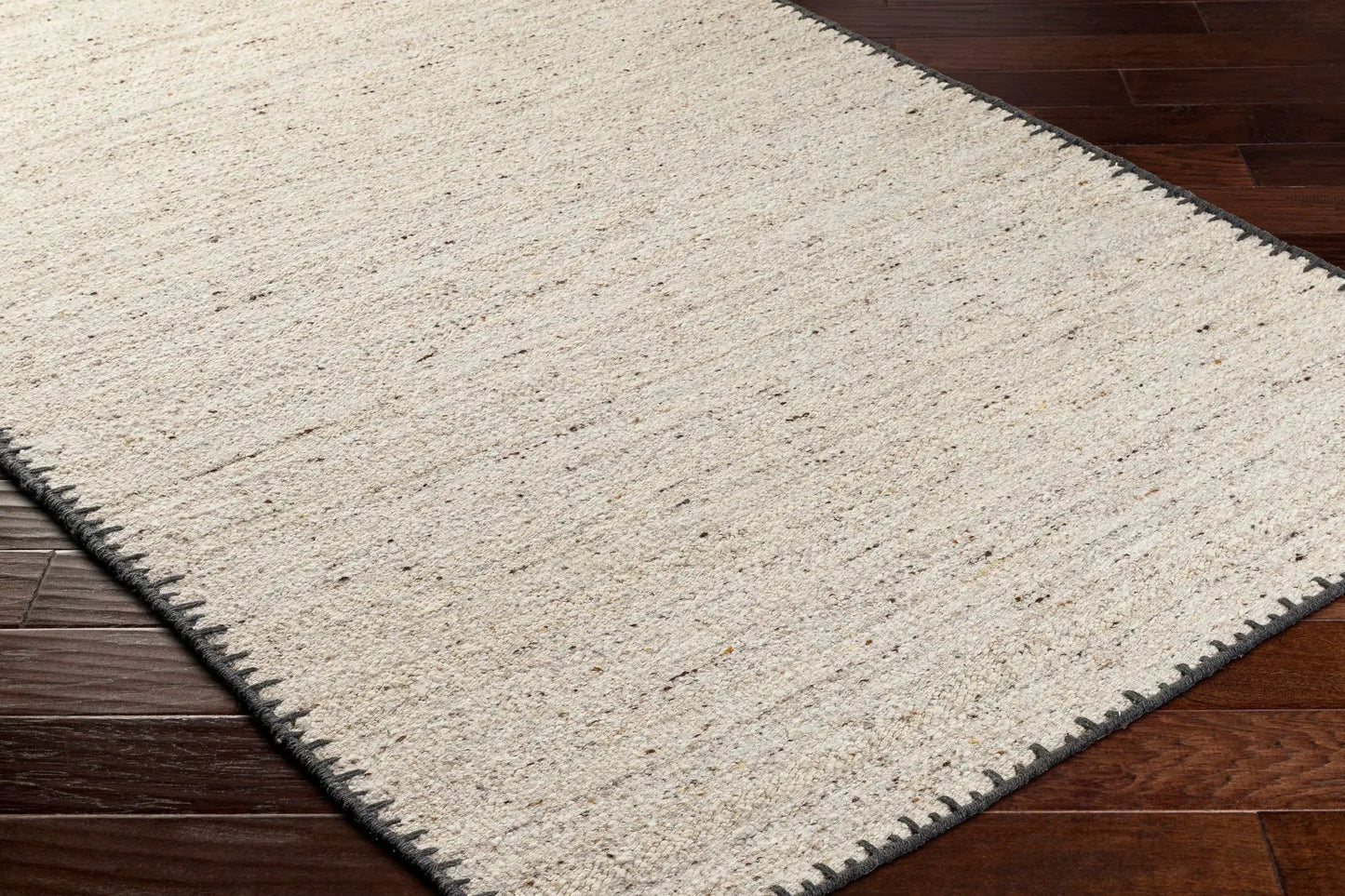 Ayumu beige handwoven wool area rug by Boutique Rugs on dark wood floor with black fringe on Tampa Home & Garden Store