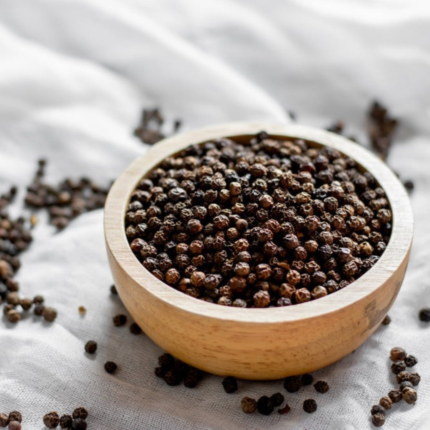 Black Pepper Plant brown peppercorns in a light wooden scoop on gray linen background on Tampa Home & Garden Store