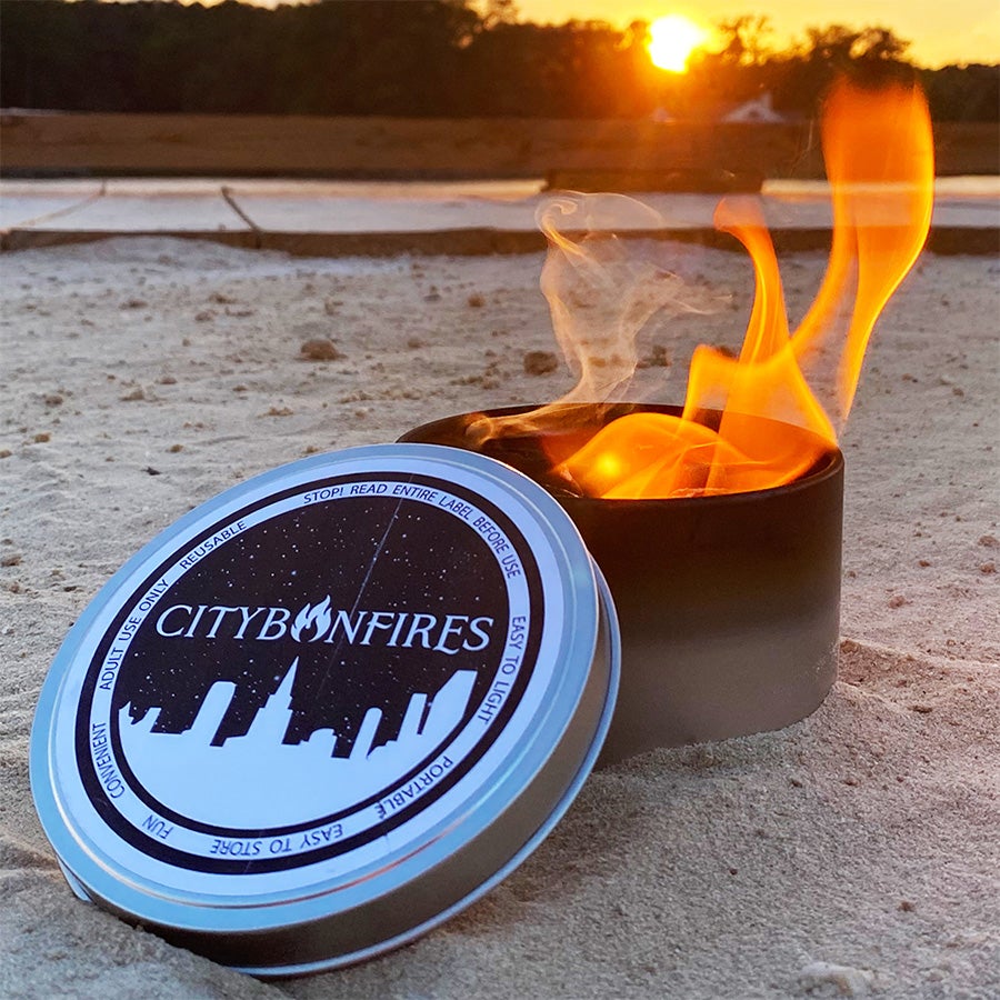 S'mores Family Pack tin by City Bonfires with skyline lid beside outdoor fire on sand at sunset on Tampa Home & Garden Store