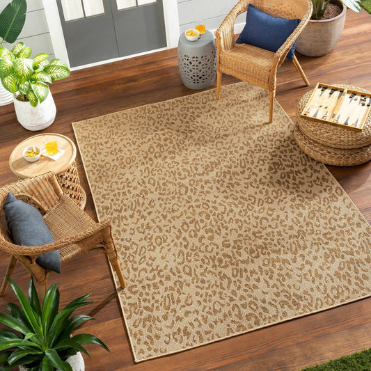 Prem Flatweave Faux Jute Outdoor Rug beige tan woven rug with wicker chair on patio on Tampa Home & Garden Store
