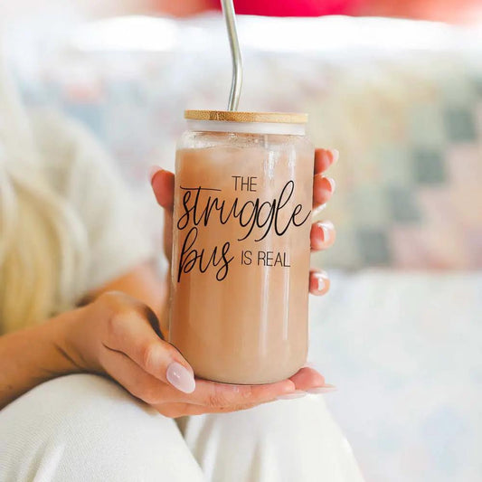Struggle Bus 17oz glass travel mug with bamboo top and straw, latte drink held by hands on Tampa Home & Garden Store