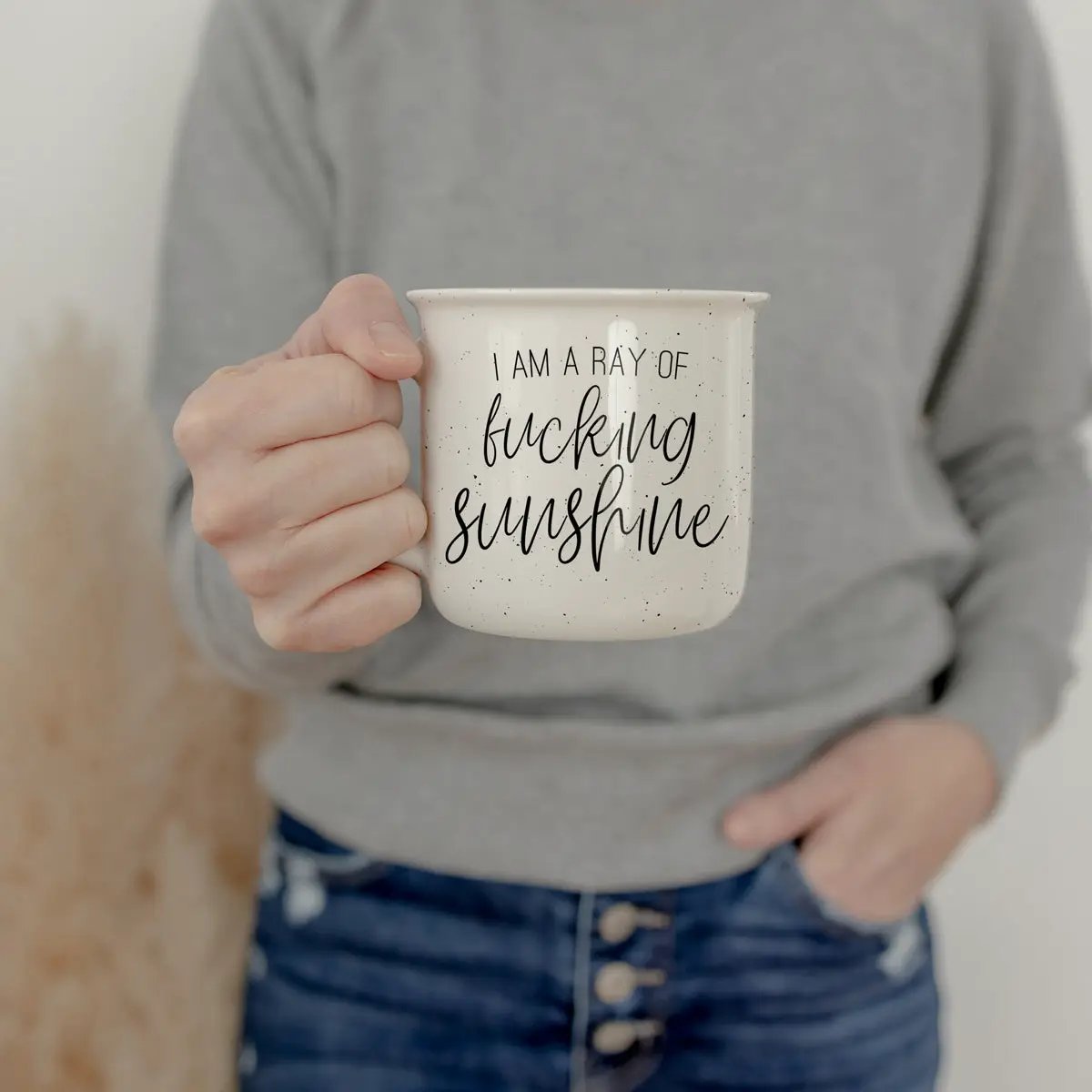Ray of F'n Sunshine mug Gia Roma, white speckled ceramic mug with black script, held on Tampa Home & Garden Store
