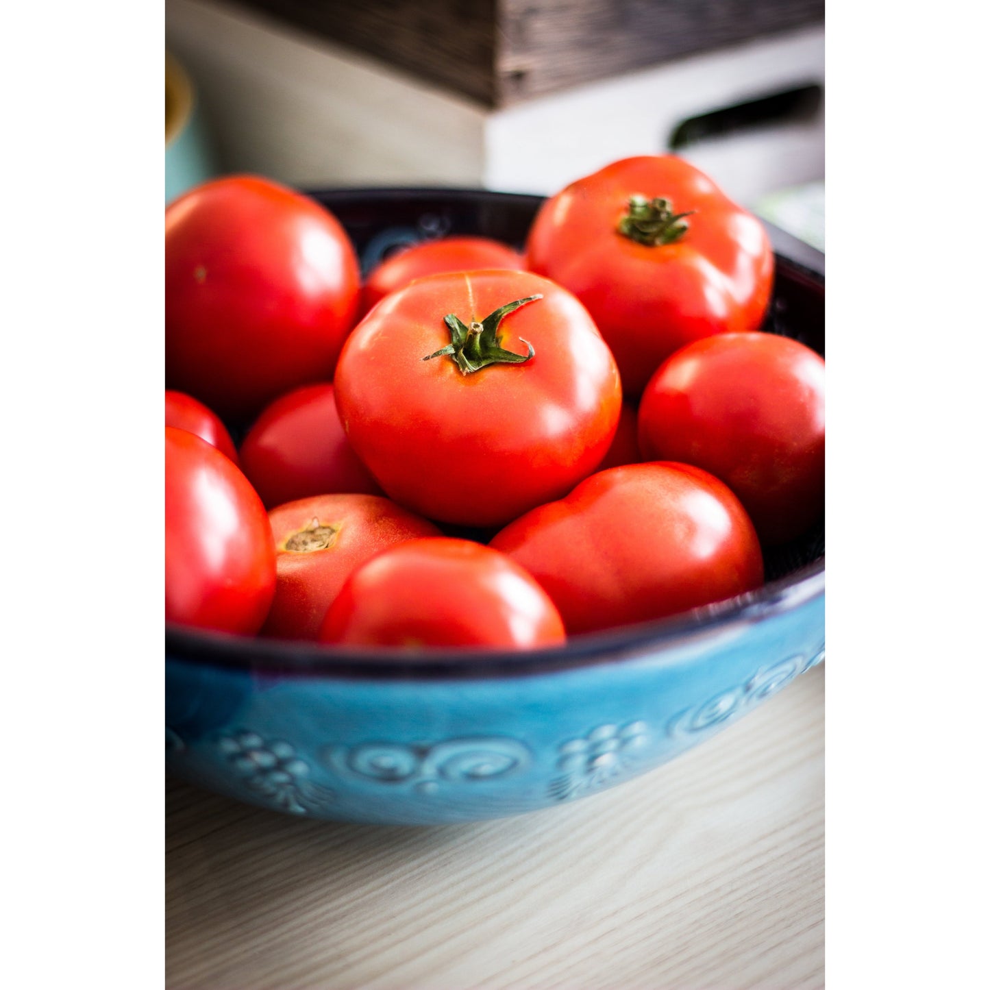 Red ripe tomatoes with green stems in a blue ceramic bowl on Tampa Home & Garden Store