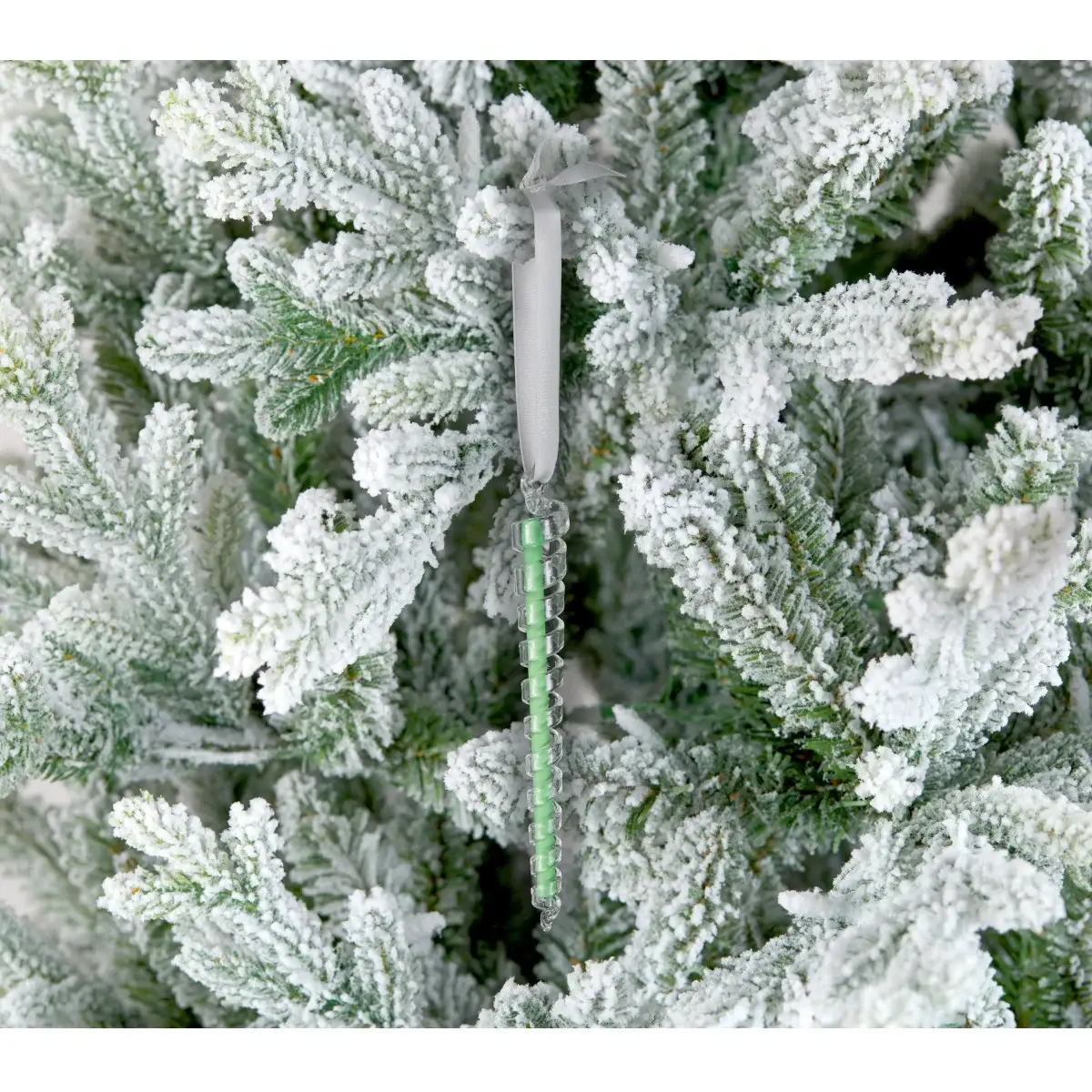 Glass icicle ornament hanging from frosted spruce with a green spiral scented stick on Tampa Home & Garden Store