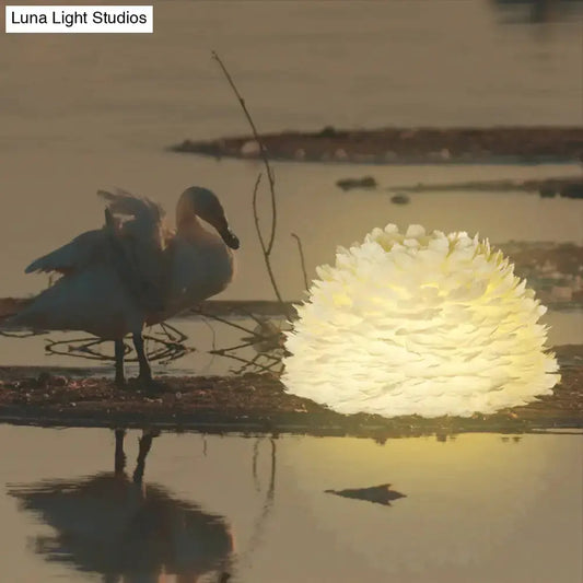 White Floral Pendant Chandelier With Feather by Decorbites, spherical white light fixture with warm glow beside a swan on Tampa Home & Garden Store
