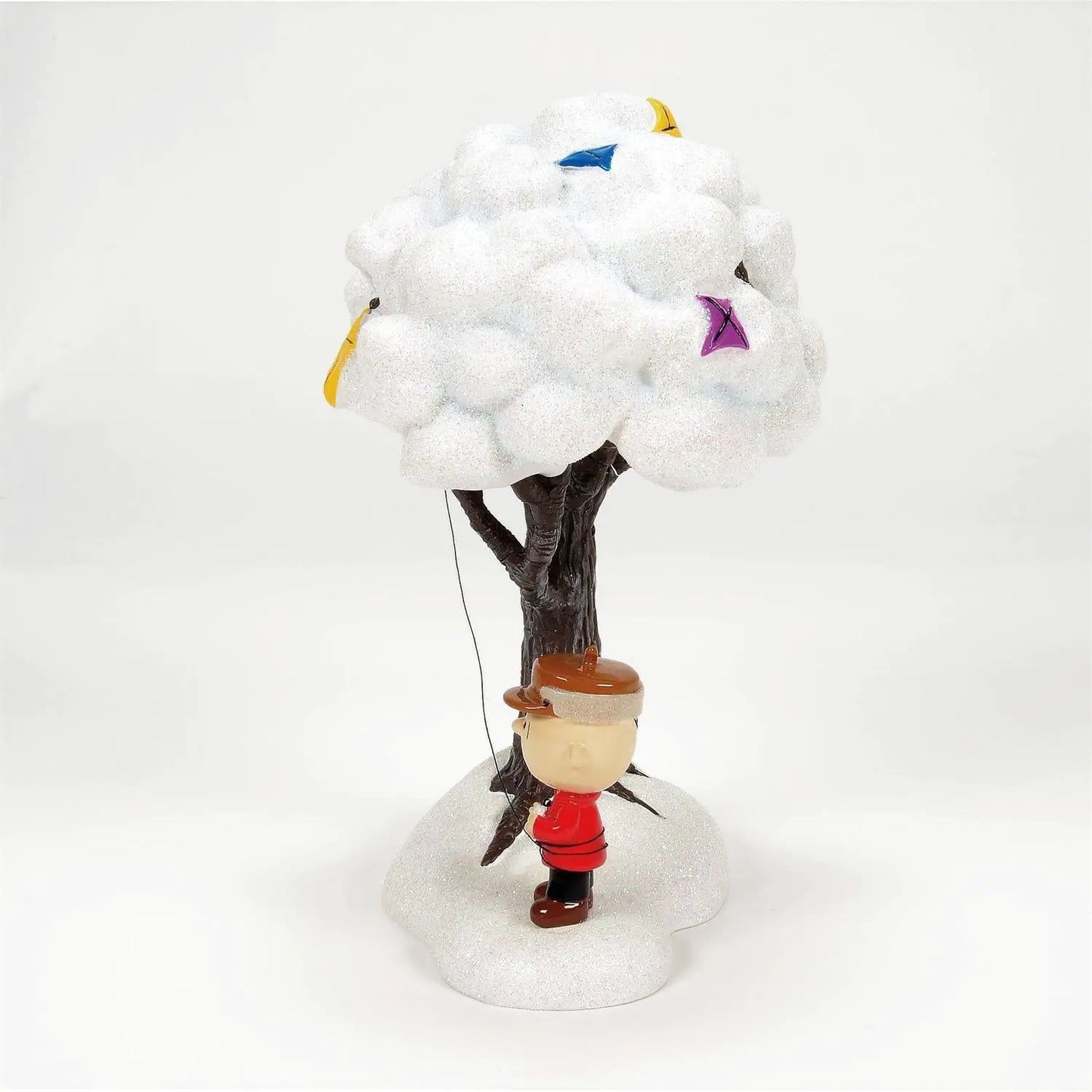 Charlie Brown Peanuts figurine with kite atop a snowy tree in a winter village scene on Tampa Home & Garden Store