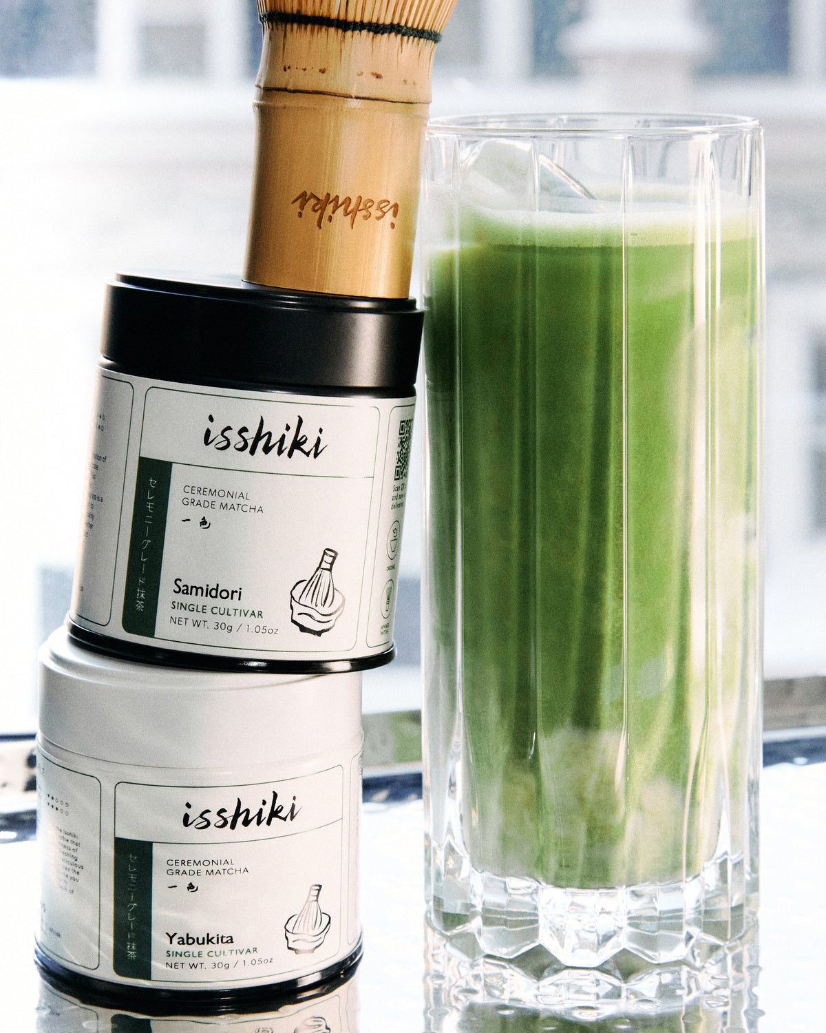 Bamboo matcha whisk (chasen) by isshiki matcha beside a tall glass of green matcha beverage on Tampa Home & Garden Store